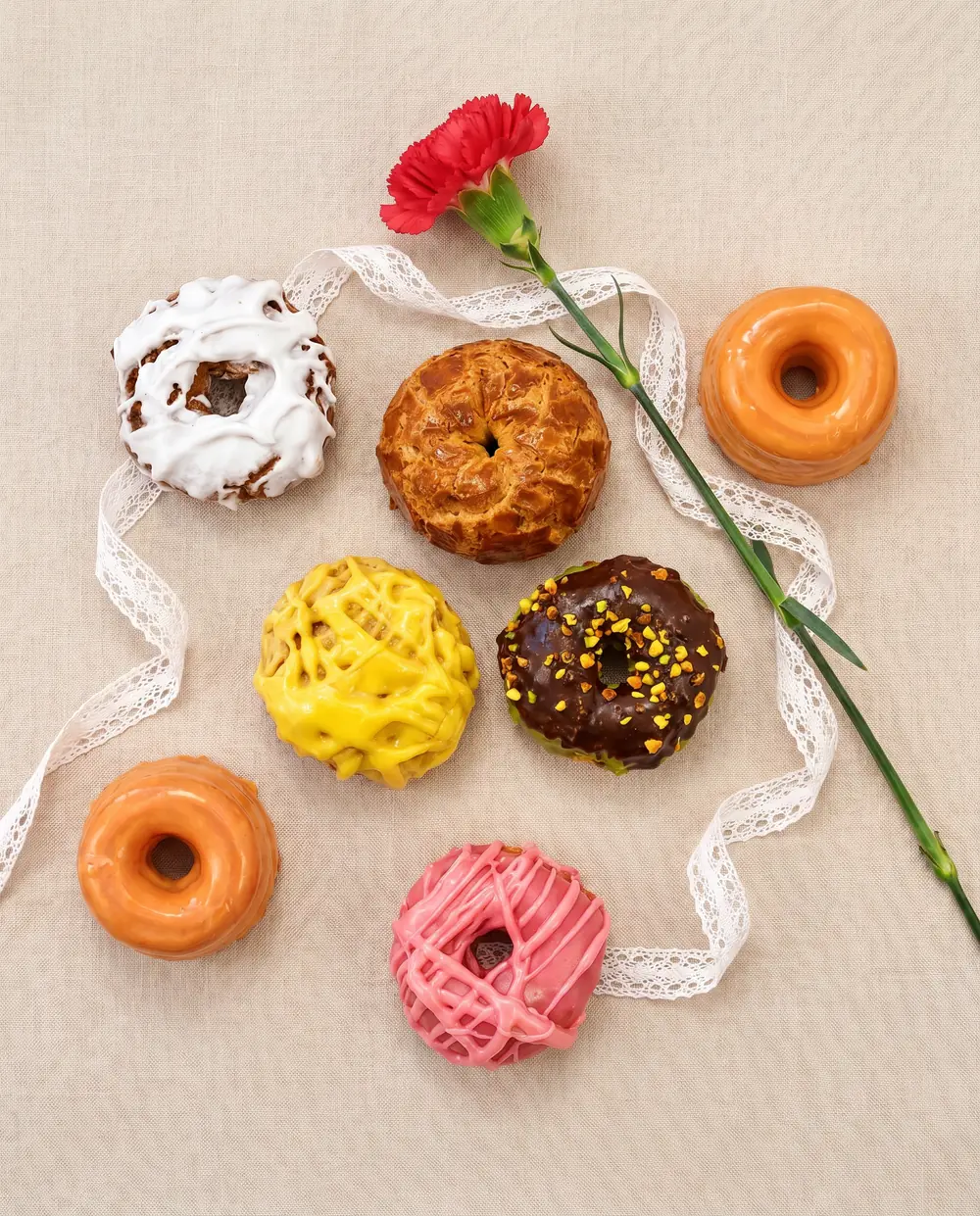 Rosquillas de San Isidro de La Mallorquina con clavel rojo y encaje, bodegón creado con IA